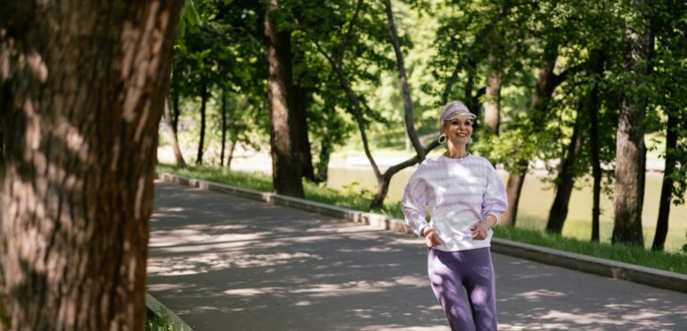 Elderly woman enjoying a refreshing jog in a lush green park during the day.