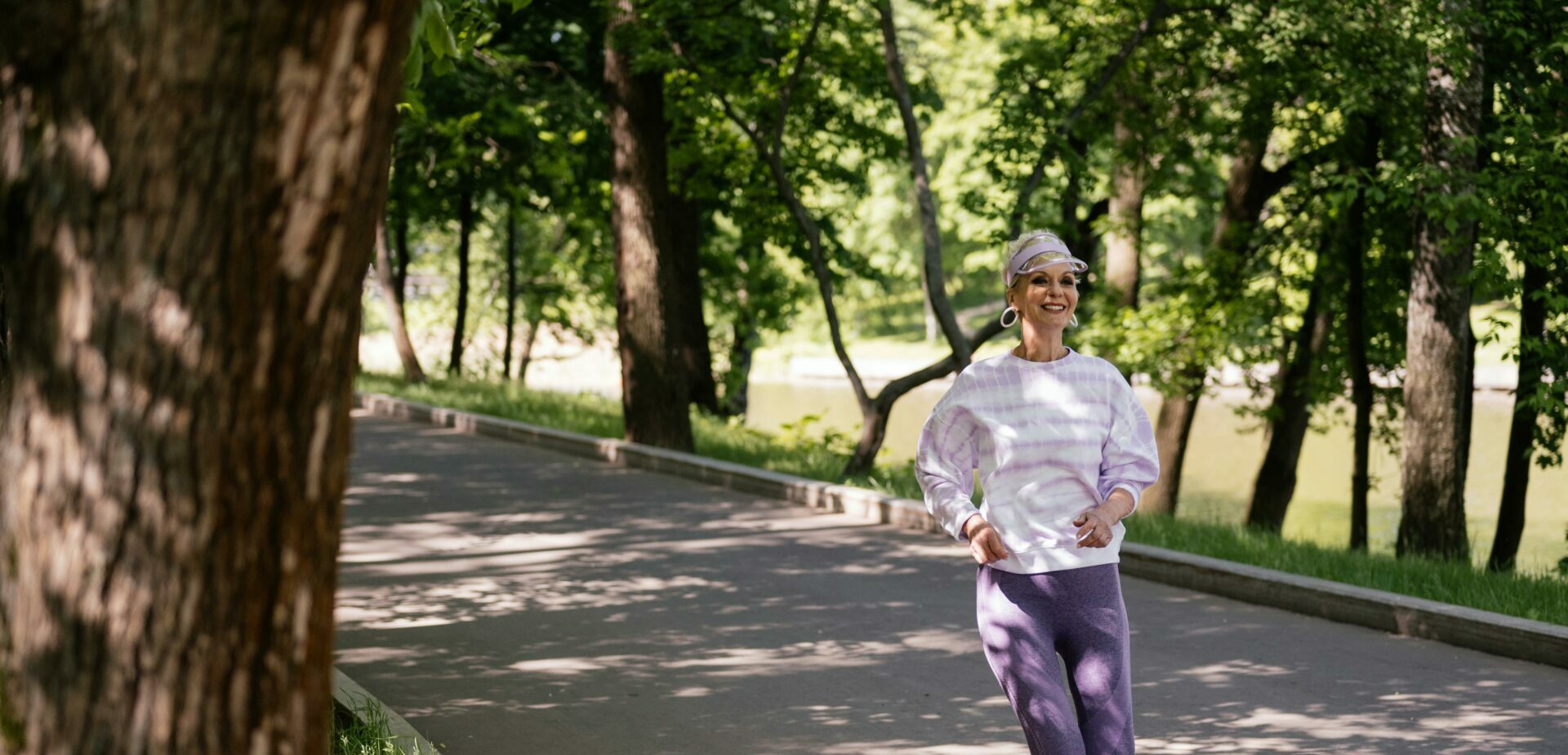 Elderly woman enjoying a refreshing jog in a lush green park during the day.