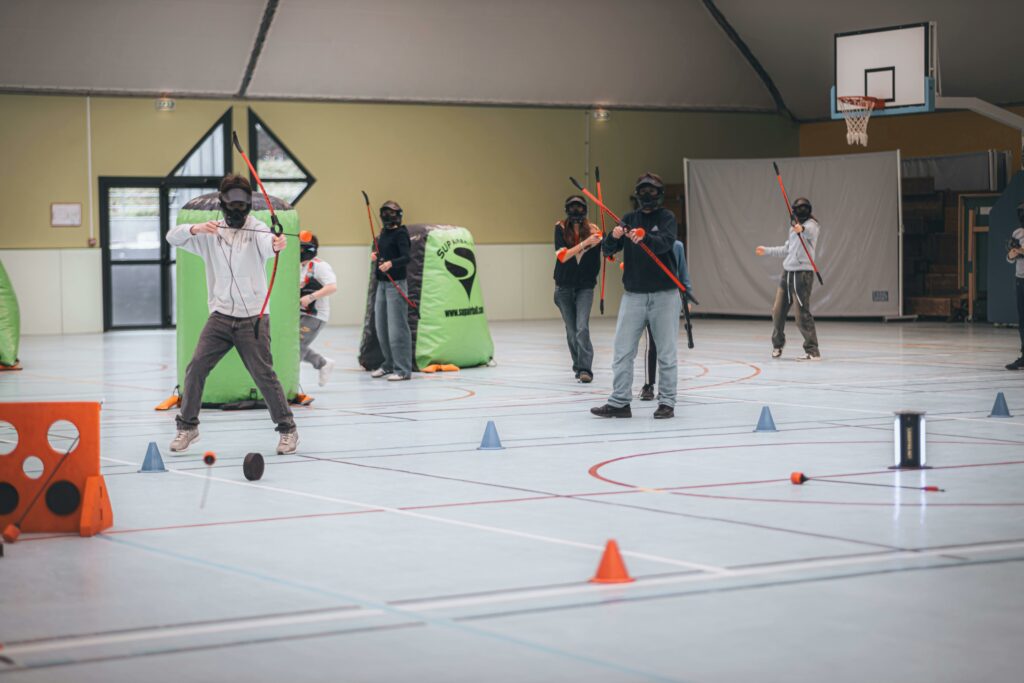 Group playing archery tag indoors with bows, arrows, and masks.