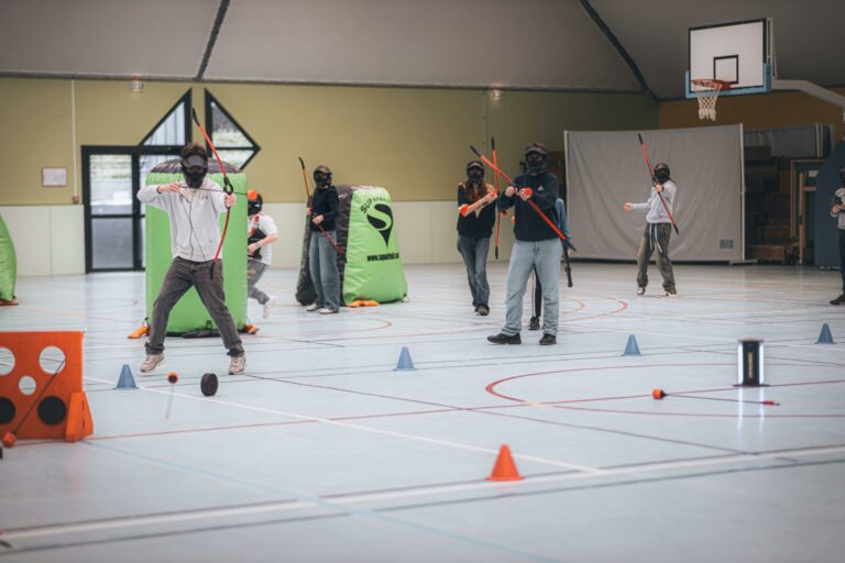 Group playing archery tag indoors with bows, arrows, and masks.