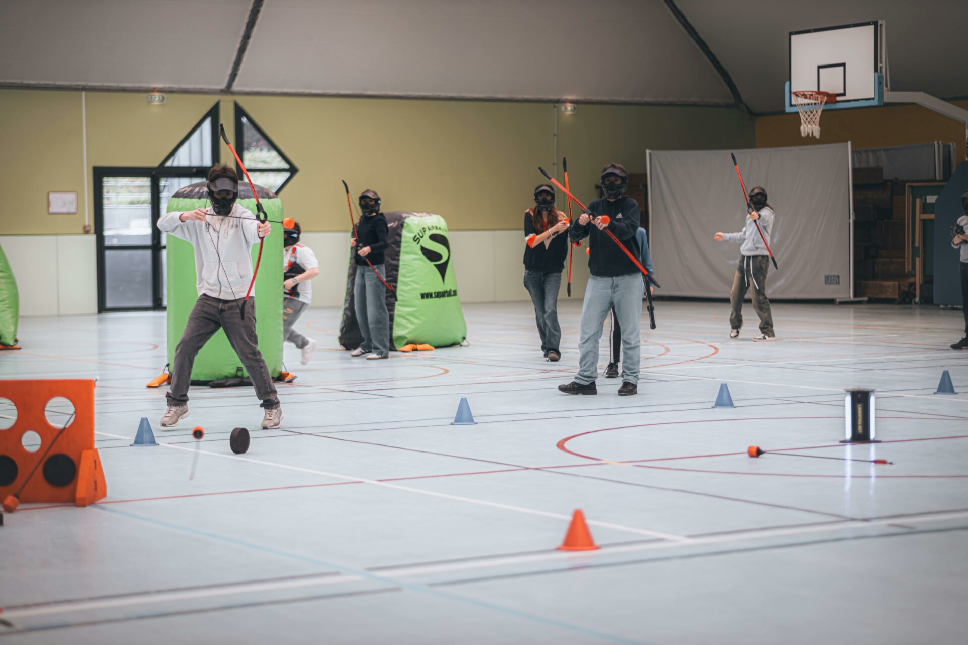 Group playing archery tag indoors with bows, arrows, and masks.